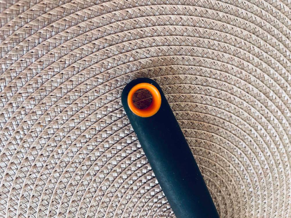 Spargelschäler-Test: orange Aufhänge-Öse eines schwarzen Modells der Marke Fiskars auf einem hellen Unterleger.