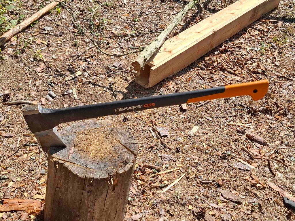 Gesamtansicht einer getesteten Fiskars-Axt, die mit dem Spalter in einem Holzstumpf steckt.