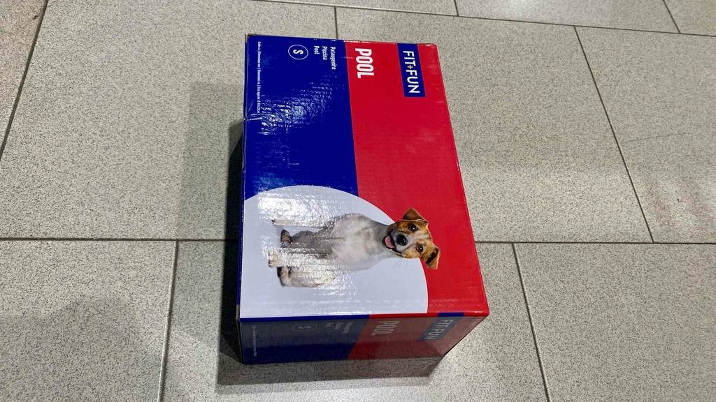 Eine blau-rote Verpackung mit einem Fit-Fun Hundepool der Größe S liegt zum Test bereit auf einem hellen Boden.
