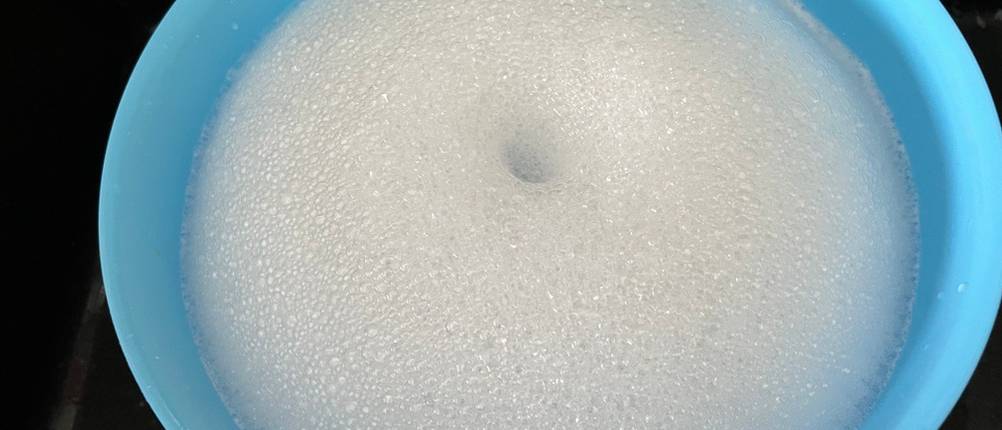 Eine blaue Schüssel mit Wasser und Schaum.