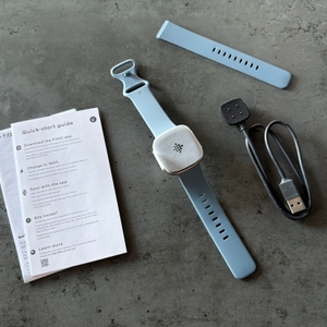 Der Lieferumfang der Fitbit Versa 4 liegt auf einem Tisch