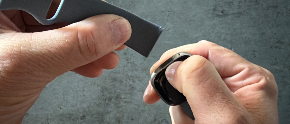 Eine Hand befestigt ein Armband der Fitbit Versa 4