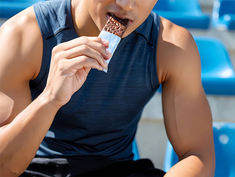 Fitness-Adventskalender-Test: Ein trainierter Mann, der in einen Fitness-Riegel beißt. 
