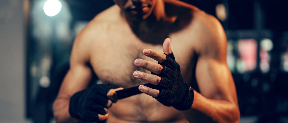 ein Mann zieht sich Fitness-Handschuhe an
