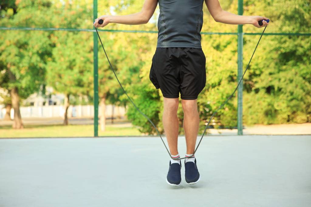 Fitness-Springseil-Test: Ein Mann trainiert mit einem Springseil auf einem Sportplatz. 