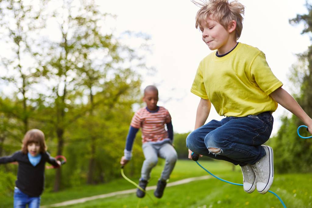 Fitness-Springseil-Test: Mehrere Kinder springen in einem Park mit einem Springseil. 