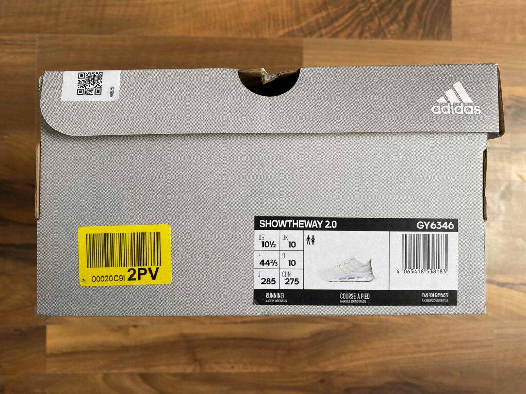 Fitnessschuh-Herren Test: Seitenansicht eines Originalkartons der Fitnessschuhe für Herren auf einer Holzoberfläche.