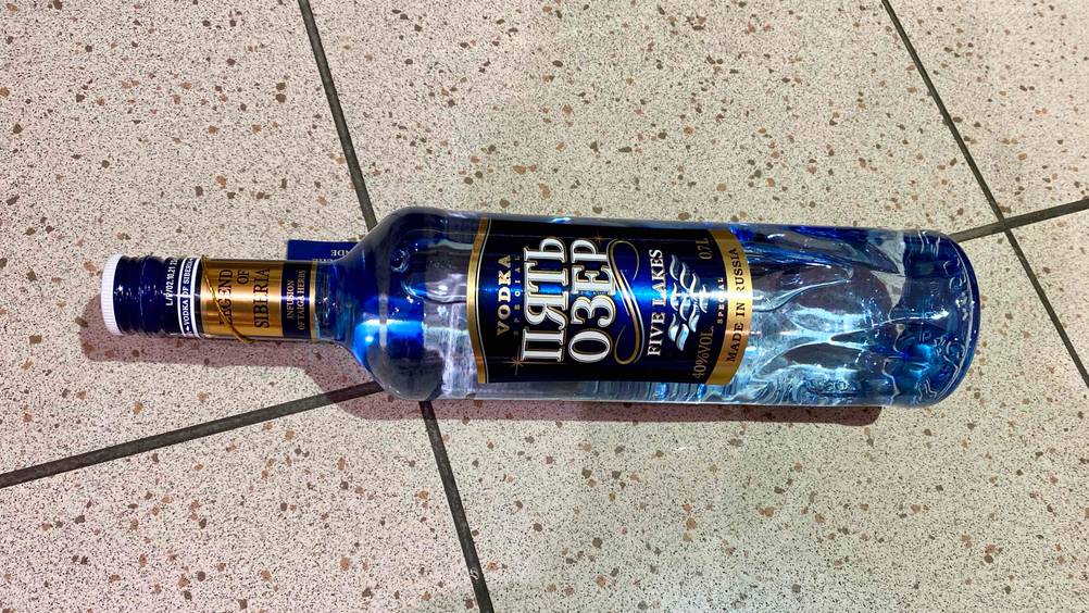 Eine Flasche des getesteten russischen Wodkas liegt horizontal auf einem Fließenboden.