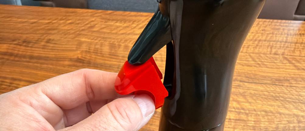 Eine Hand entfernt eine Sicherung vom Hebel vom Flairosol-Olivia-Olivenöl-Sprüher