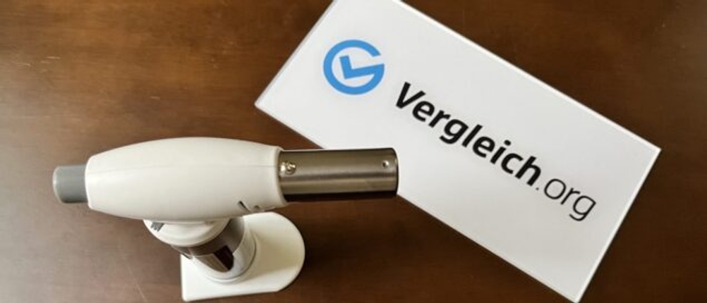 Flambierbrenner steht neben einem Schild mit der Aufschrift Vergleich.org.