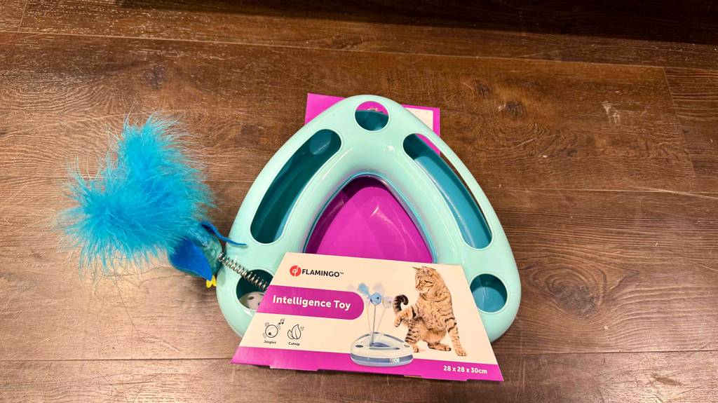 Ein Intelligenzspielzeug für die Katze liegt zum testen auf einer Holzfläche.