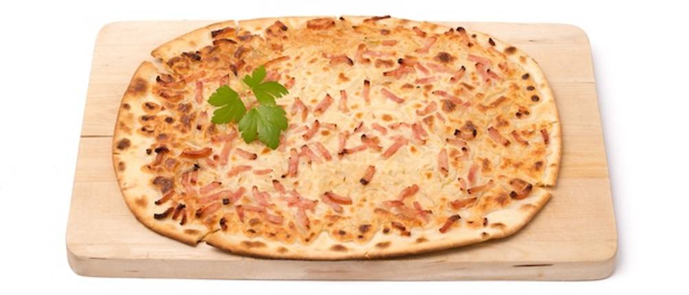 Flammkuchenbrett getestet: Vor einem weißen Hintergrund ist ein rechteckiges helles Flammkuchenbrett mit einem ganzen Flammkuchen abgebildet.
