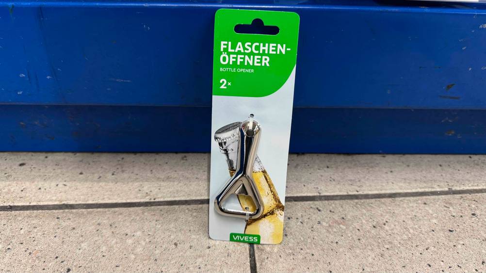 Ein getesteter Flaschenöffner lehnt an einem blauen Regal.