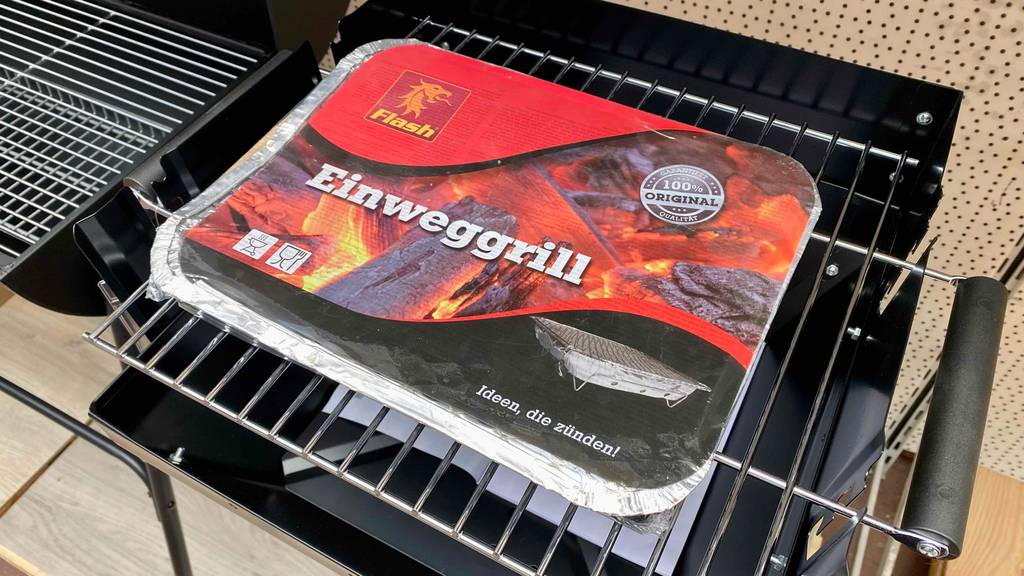 Einweggrill im Test: Verpackter Einweggrill steht auf herkömmlichen Grillrost.