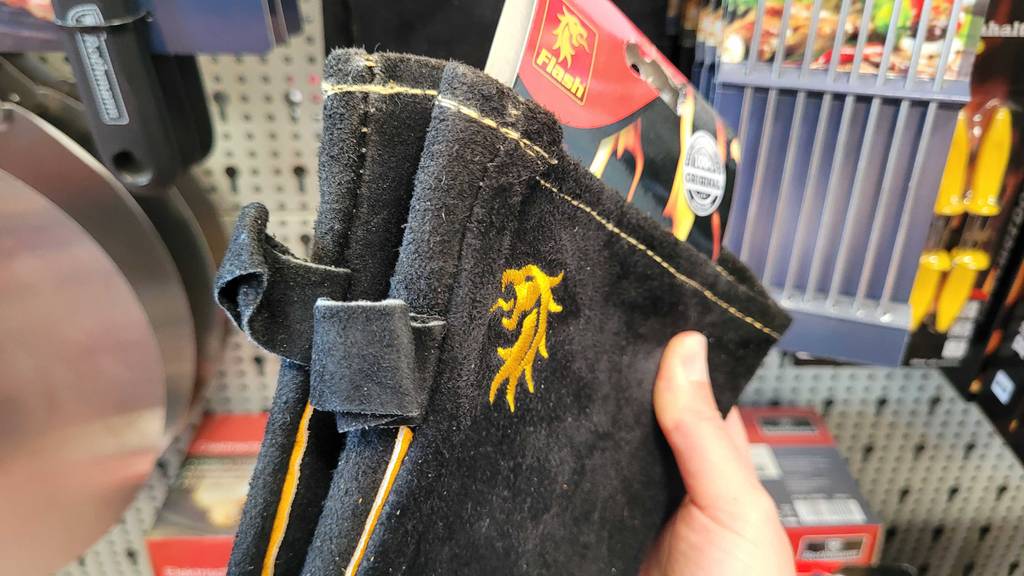 Nahansicht einer Hand, die ein Paar getestete Grillhandschuhe hält.