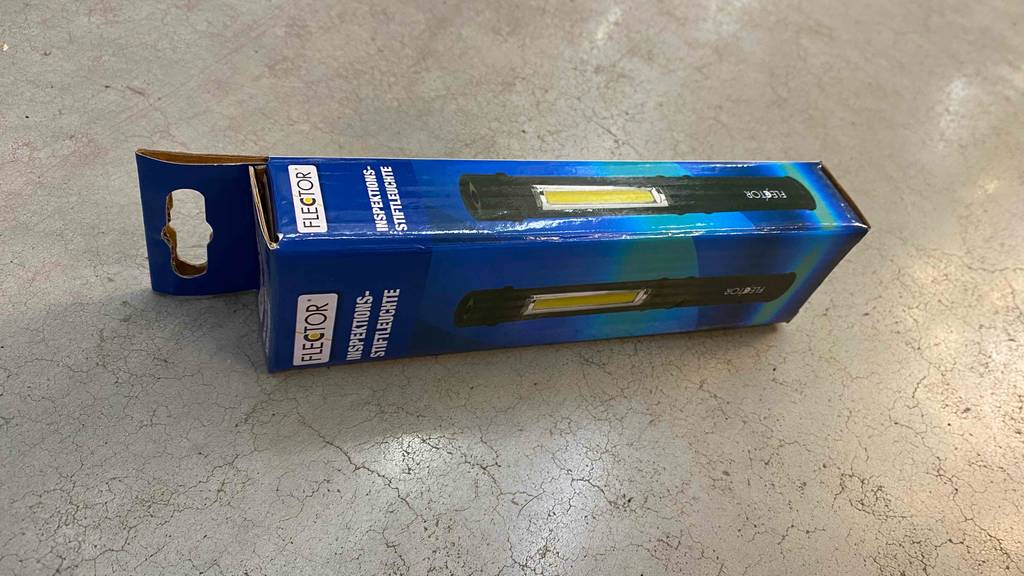 Stiftlampe im Test: eine verpackte Lampe von Flector liegt quer auf einem Fliesenboden.