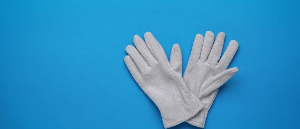 Fleece-Handschuhe-Test: Graue Fleece-Handschuhe liegen auf einem blauen Hintergrund.