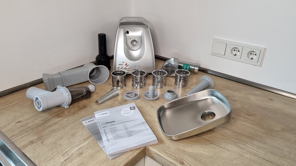 Bosch MFW68660 Fleischwolf in allen Einzelteilen auf einer Arbeitsfläche aufgestellt.