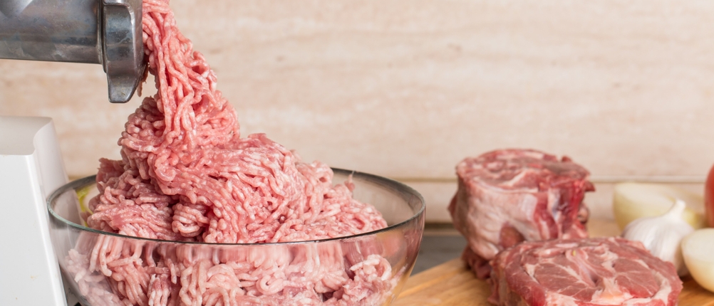 Fleisch wird durch einen Fleischwolf gepresst
