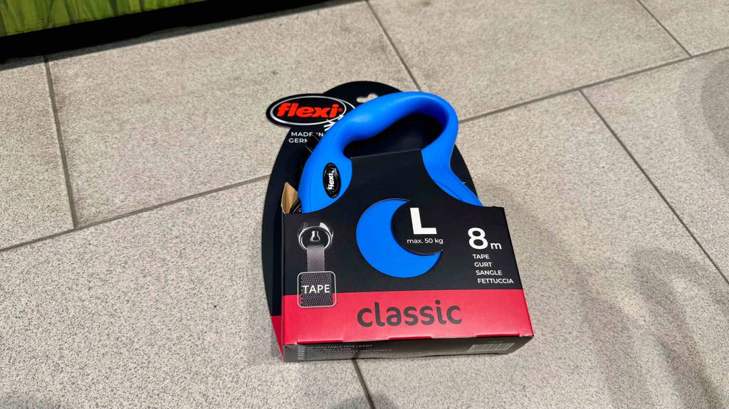 Eine getestete Flexi-Leine für große Hunde liegt in Originalverpackung auf einem Fliesenboden.