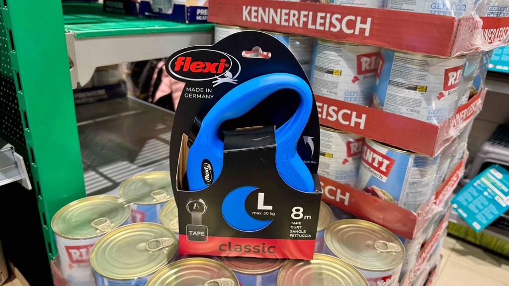 Eine verpackte Flexi-Leine für große Hunde steht zum testen auf mehreren Dosen Hundefutter.
