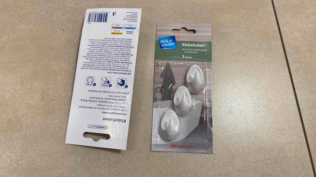 Getestete Klebehaken von Flink-Sauber: zwei Verpackungen inklusive Anwendungsbeschreibung liegen auf dem Boden.