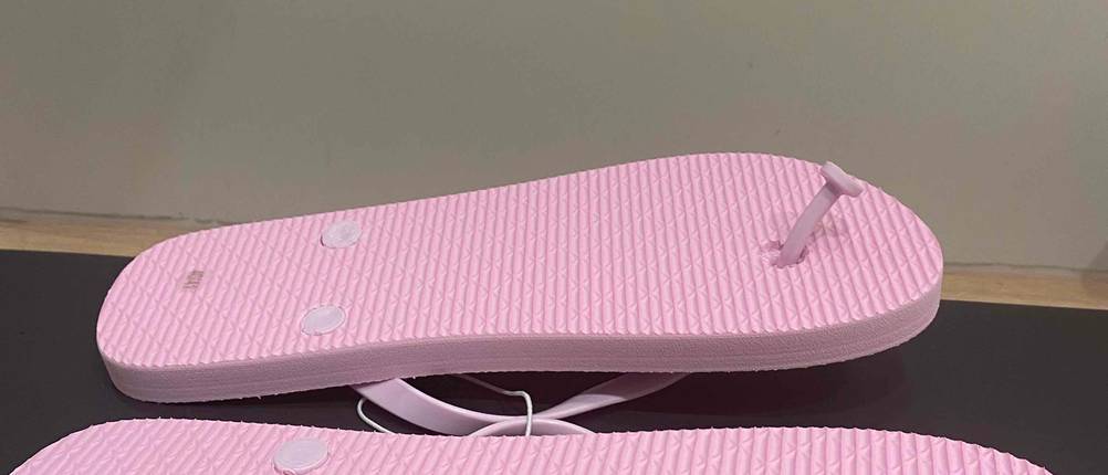 Flip-Flop-Damen-Test: Ein Paar Flip-Flop für Damen mit der Sohle nach oben auf einer dunklen Fläche.