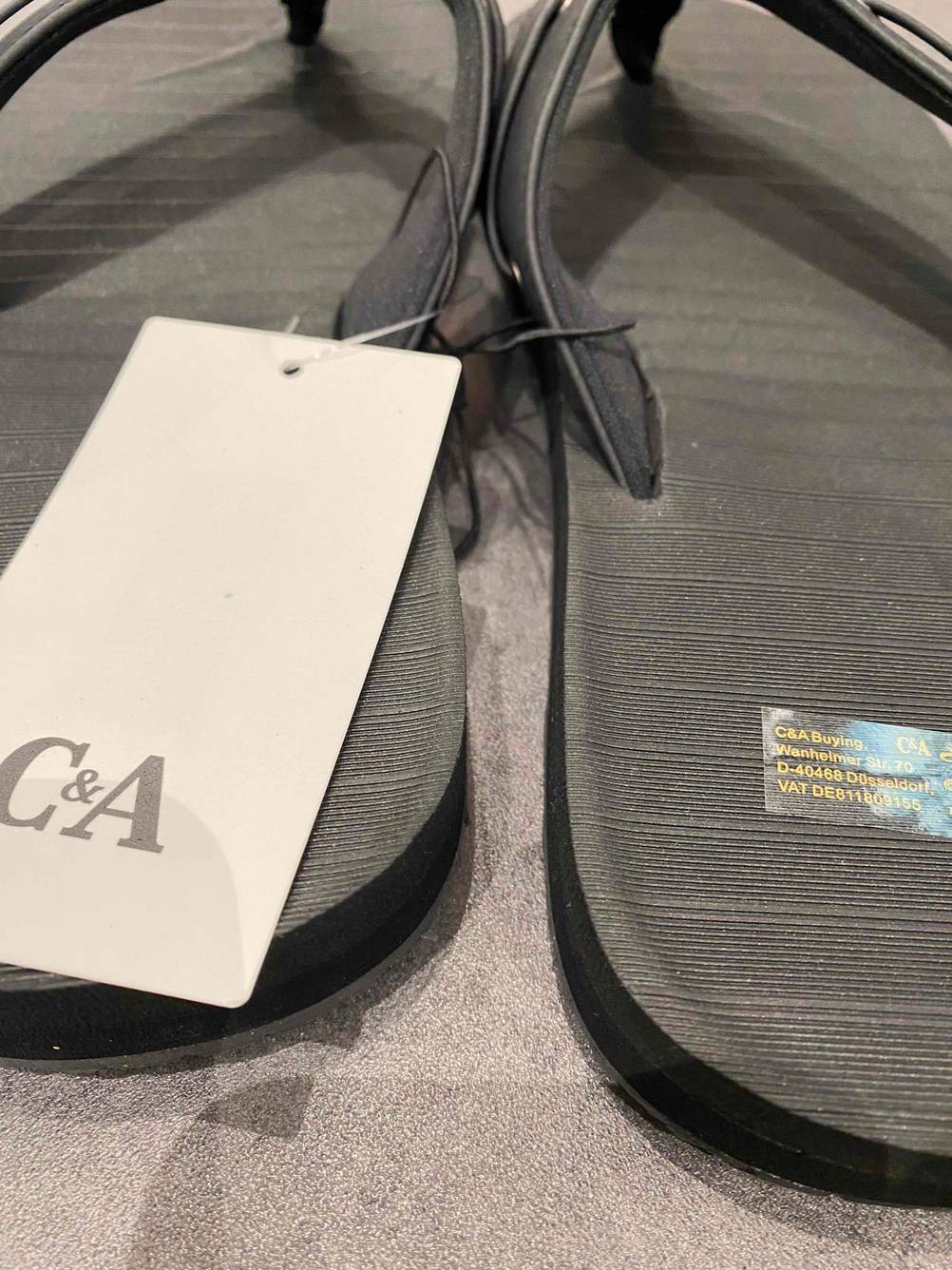 Getestet: Zwei Flip-Flop für Herren in Nahaufnahme von hinten mit Label der Marke.