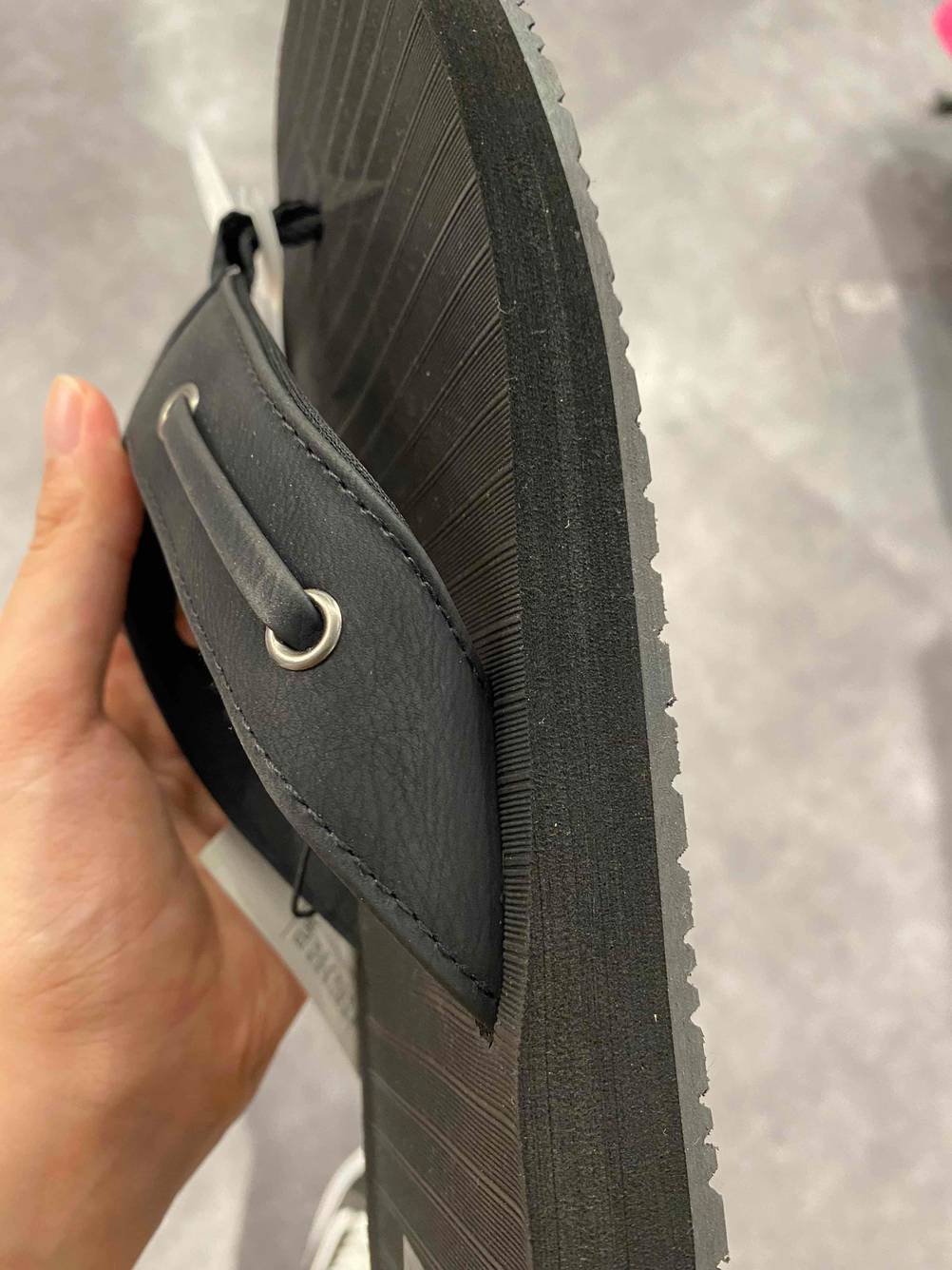 Nahaufnahme der Seite eines getesteten Flip-Flop für Herren von einer Hand hochgehalten.