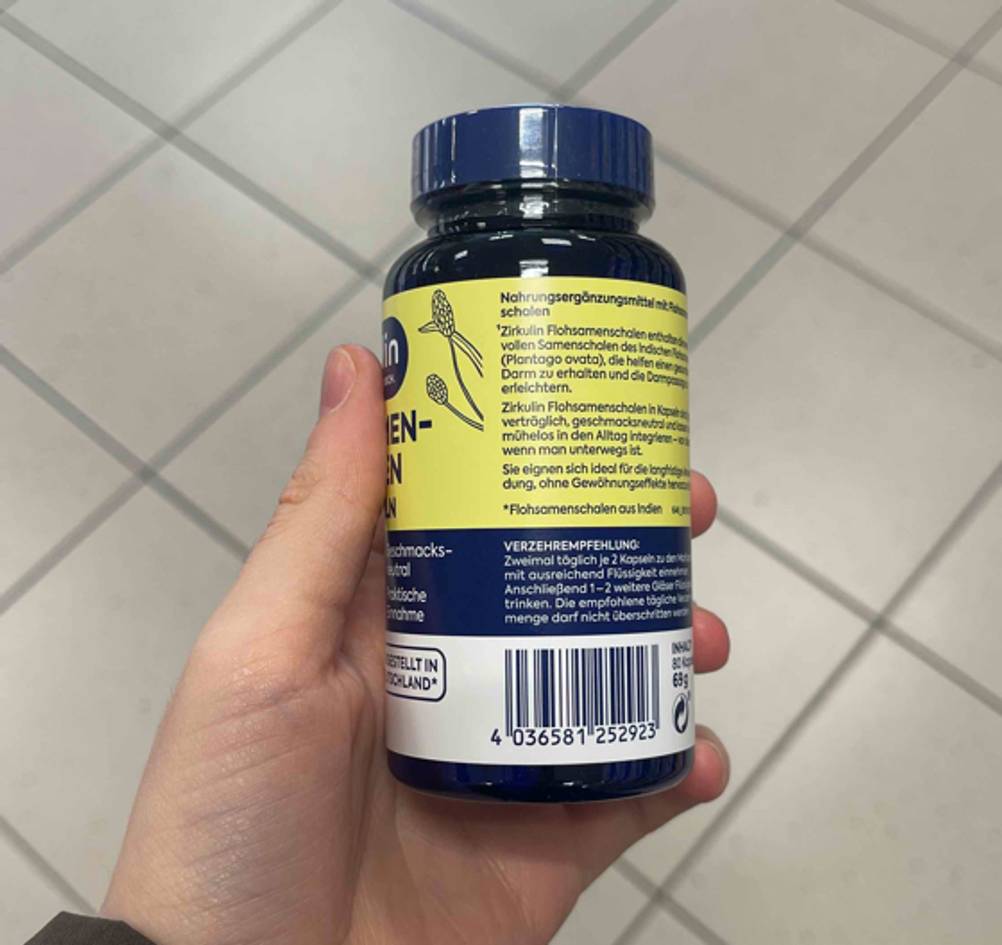 Eine Hand hält die Dose Flohsamenschalen-Kapseln im Test hoch.