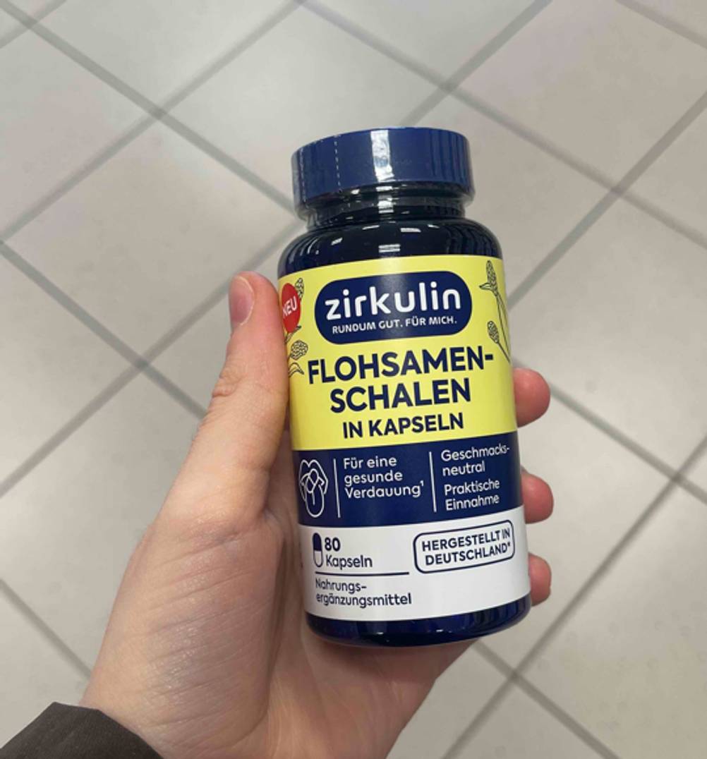 Getestet: Eine Hand hält eine Dose Flohsamenschalen-Kapseln.