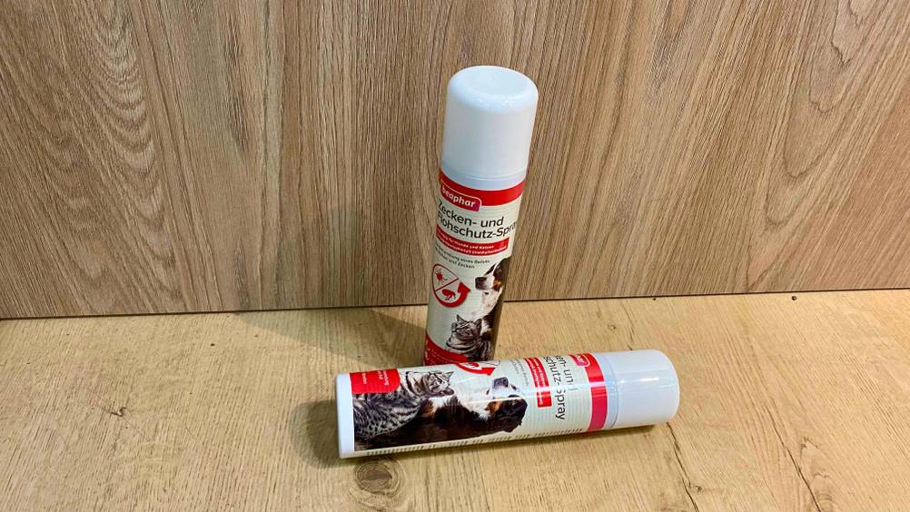 Flohspray getestet: Zwei Dosen, eine stehend eine davor liegend auf einer Holzfläche.