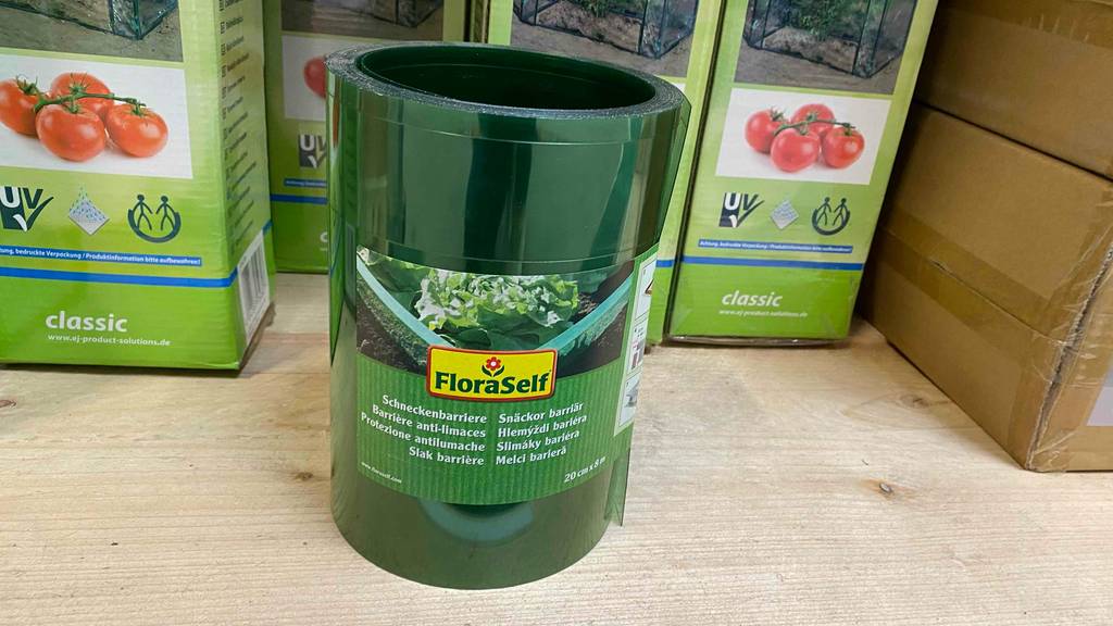 Schneckenzaun-Test: Eine Verpackung mit eingerolltem Schneckenzaun in acht Meter Länge und zwanzig Zentimeter Höhe steht vor eingepackten Tomaten-Zuchtbecken.