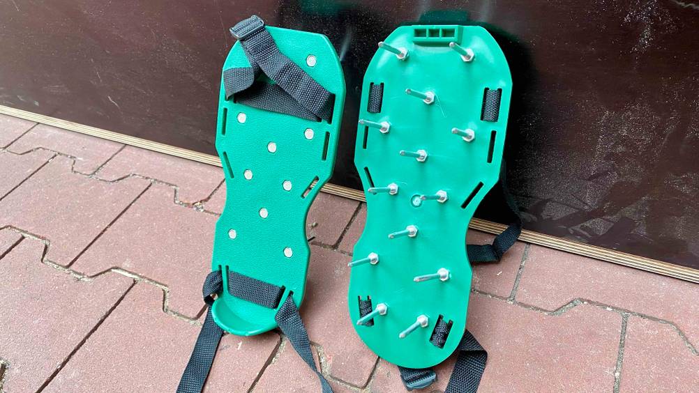 Rasenlüfter-Schuhe getestet: Ein Paar lehnt an einer dunklen Wand, einmal Vorderseite, einmal Rückseite.