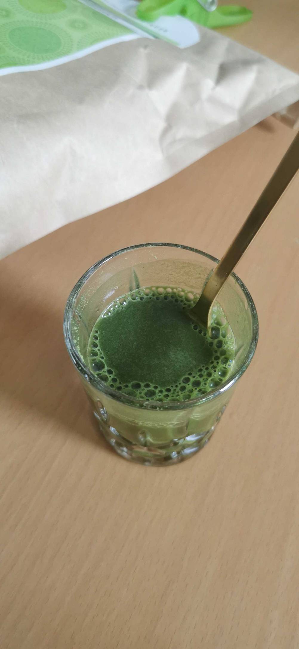 Im Test: Ein Glas mit angerührtem Gerstengras-Pulver in dem ein Löffel steckt.
