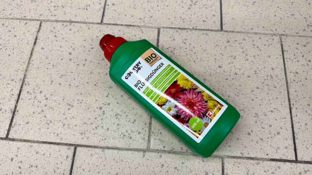 Auf einem Fließenboden liegt eine Flasche des getesteten Flüssigdüngers.