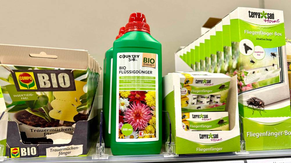 Mehrere getestete Flüssigdünger stehen in einem Verkaufsregal neben anderen Produkten.