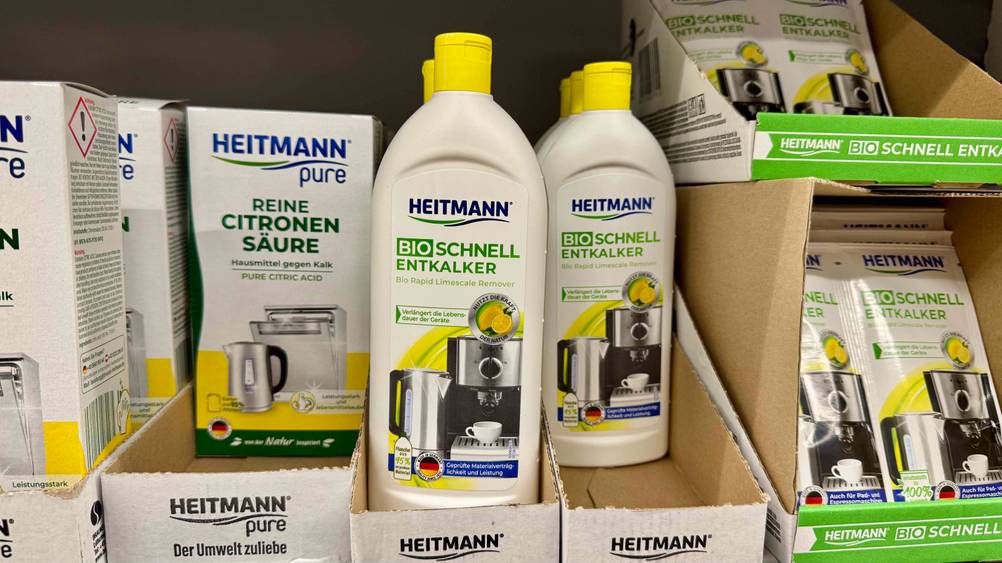 Mehrere Flaschen des Flüssigentkalker im Test in einem Regal neben anderen Produkten.