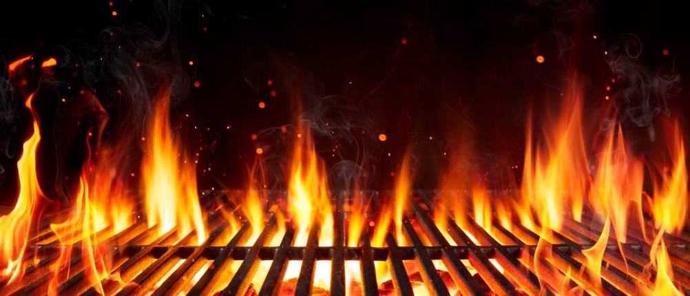 Grillrost mit durchkommenden Flammen und sprühenden Funken.