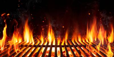 Grillrost mit durchkommenden Flammen und sprühenden Funken.