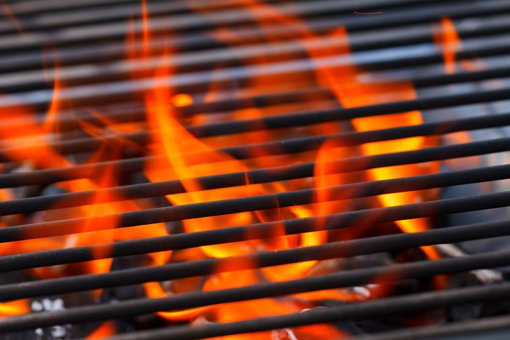 Flammen kommen zwischen einem Grillrost hervor.