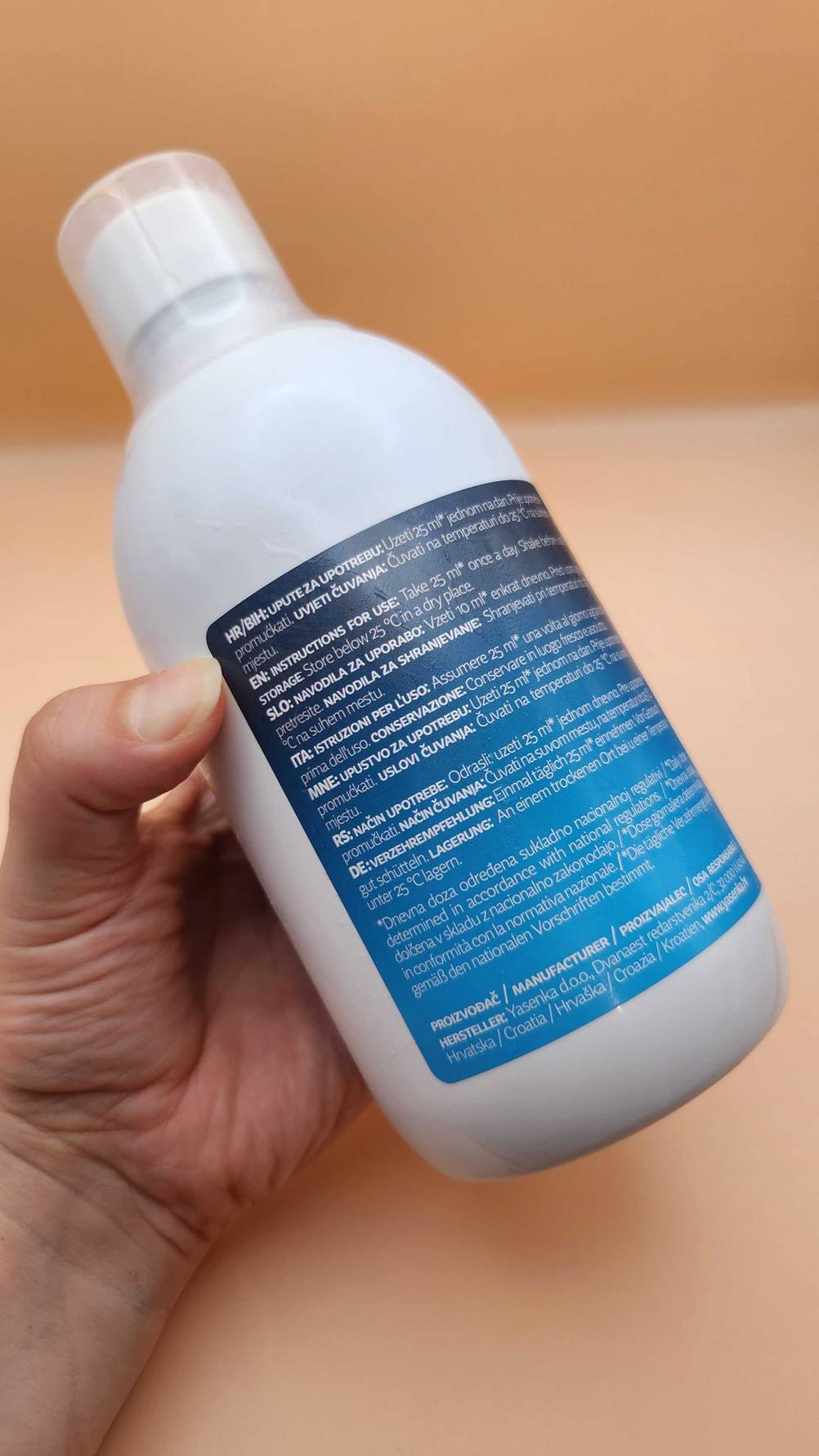 Eine Hand hält das getestete flüssige Kollagen mit der Rückseite nach vorne.