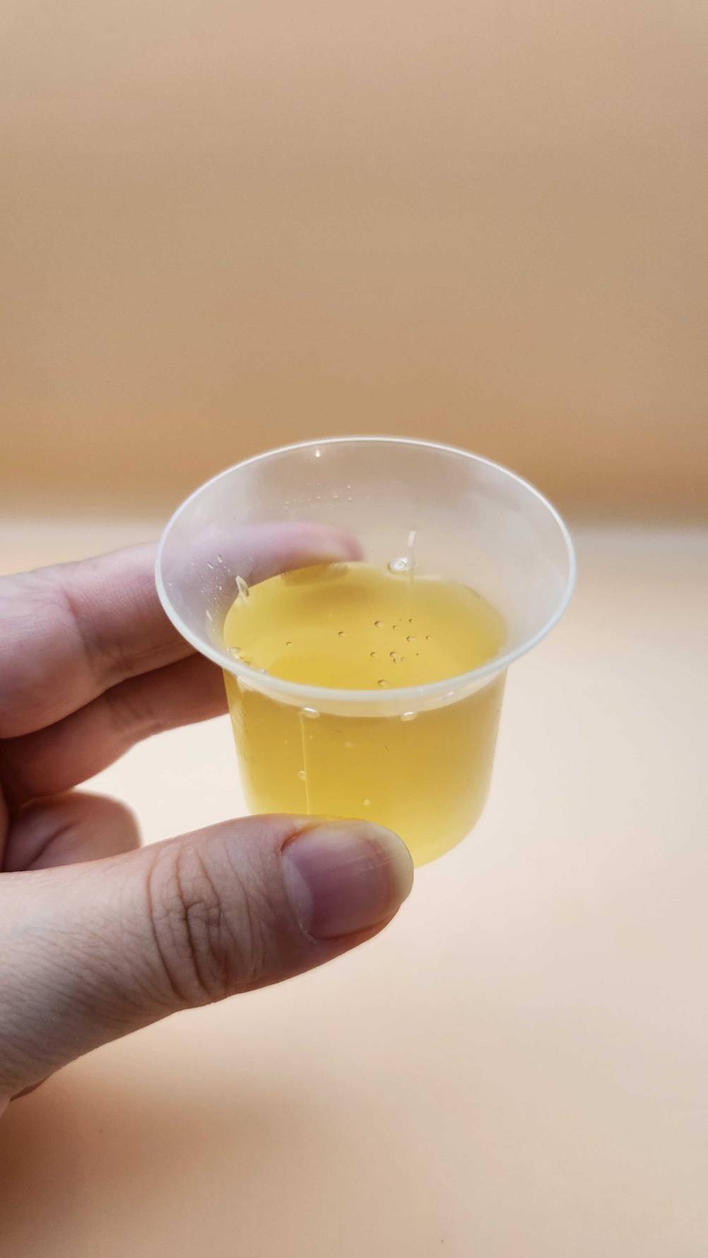Eine Hand hält einen Becher mit dem flüssigen Kollagen im Test.