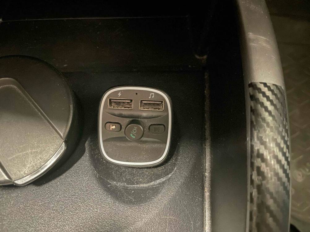 Ein schwarzer, getesteter FM-Transmitter steckt in einem Zigarettenanzünder.