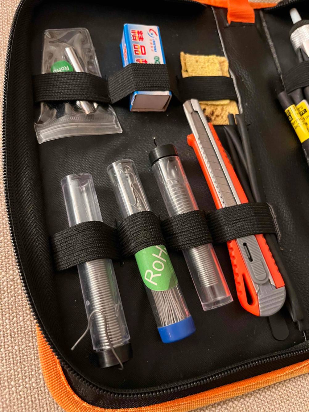 Detailaufnahme eines getesteten Lötkolben-Sets, mit Fokus auf das Lötmaterial und weiteres Zubehör.