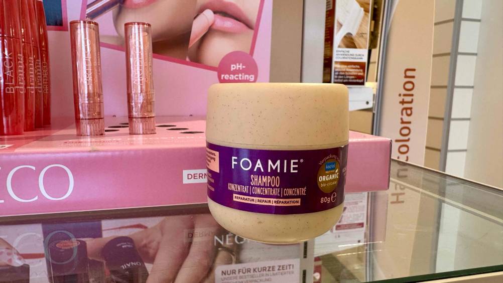 Foamie festes Shampoo im Test: Ein Block auf einer Glasfläche vor einem Aufsteller.