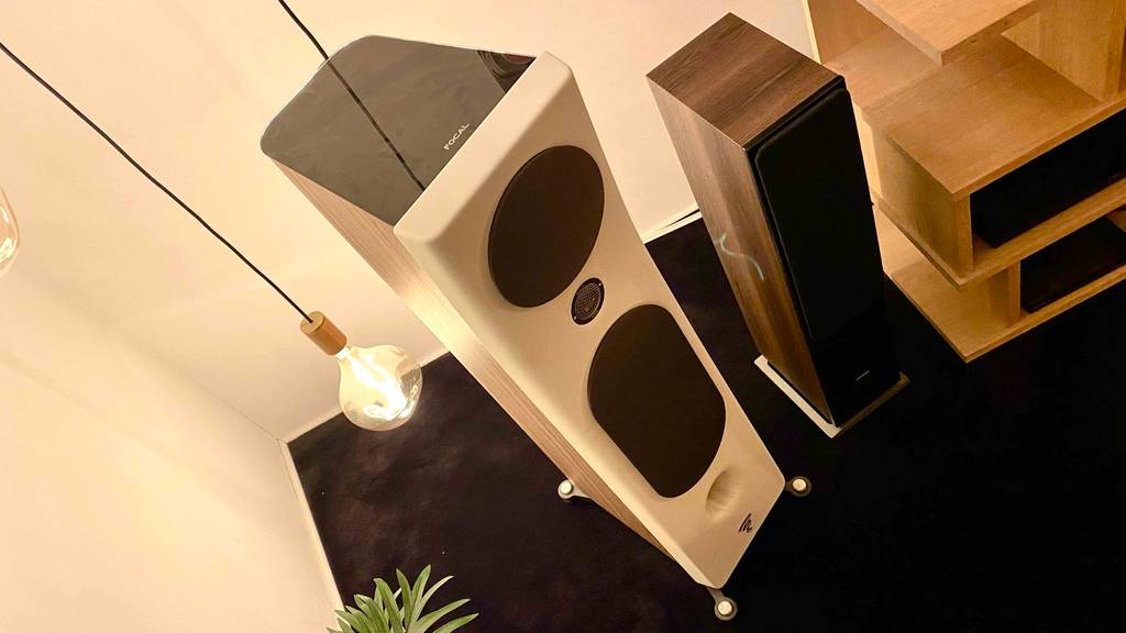 Hifi-Lautsprecher im Test von oben: ein weißer und ein Standlautsprecher aus Holz befinden sich in einem Wohnzimmer auf einem schwarzen Teppich.