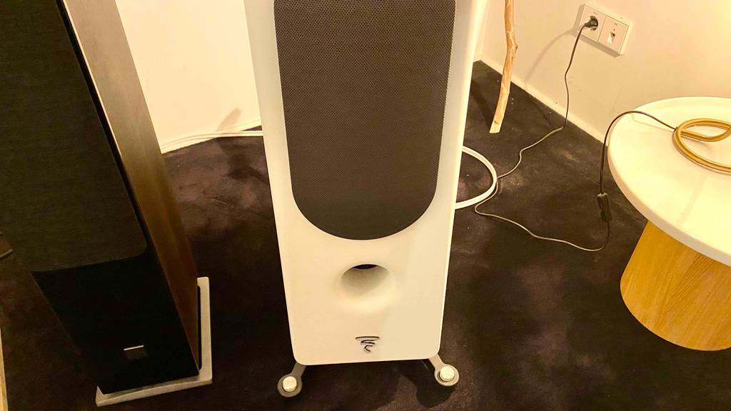 Detailansicht der Standfüße von Hifi-Lautsprechern im Test: ein weißer und ein Standlautsprecher aus Holz auf schwarzem Teppichboden.