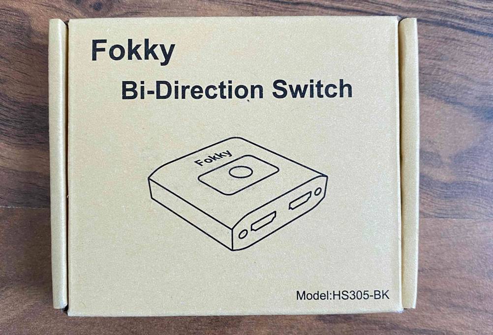 HDMI-Splitter 1 in 2 out im Test: Beigefarbener Originalkarton von einem Fokky Bi-Direktion Switch, Modell HS305-BK auf einer Holzfläche.
