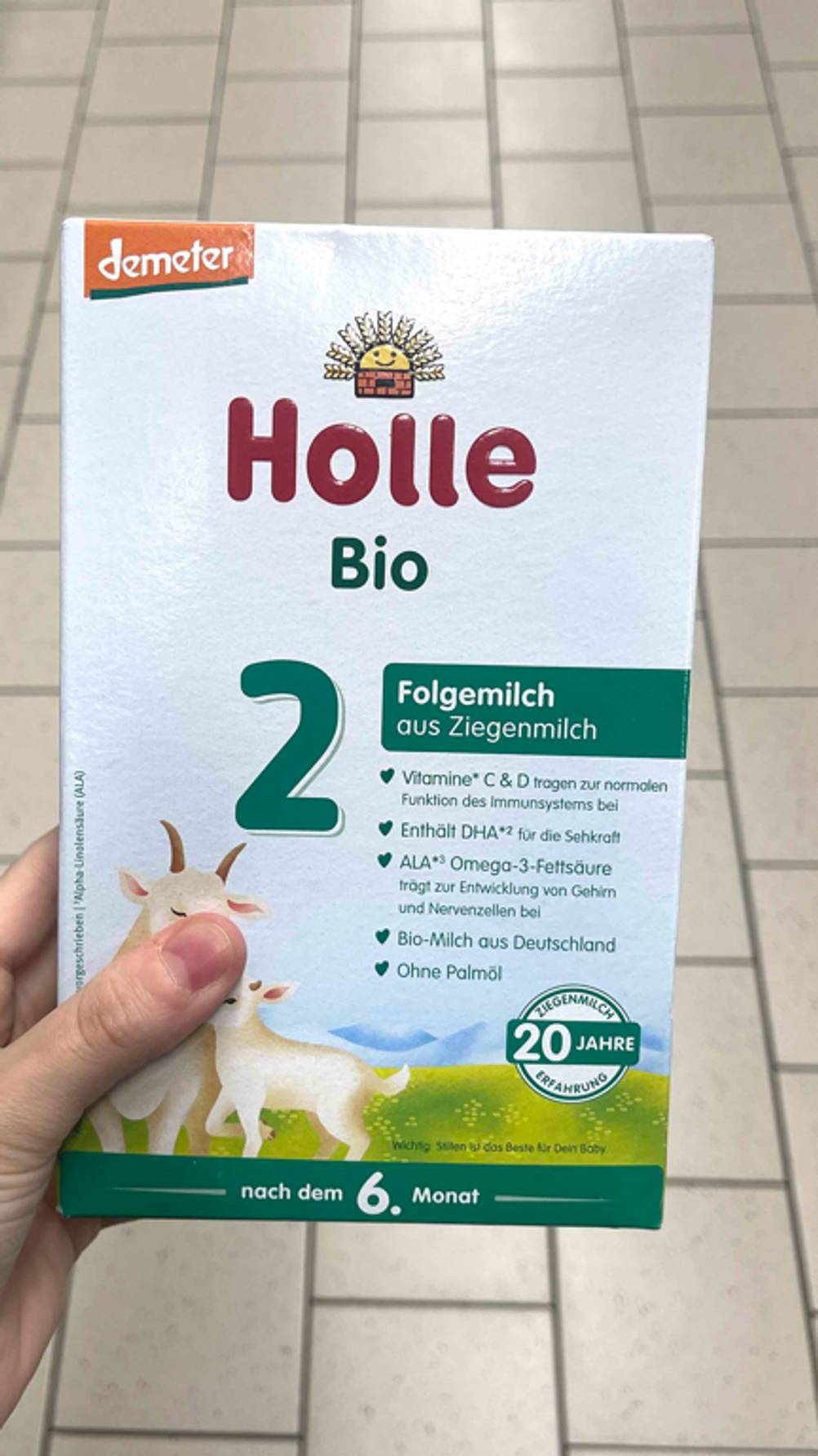 Eine Hand hält eine Packung Folgemilch 2 zum testen.